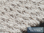 Close-up of the gray plush pet bed surface showing soft textured fabric. Text reads “Stain Resistant.”
