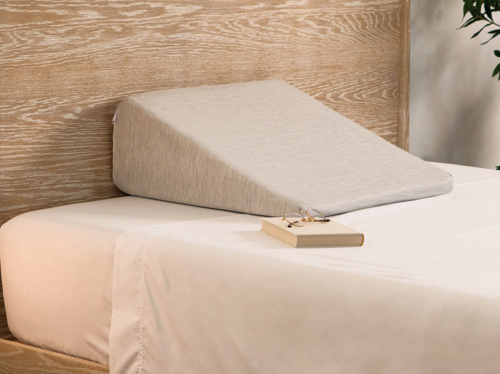 Beige wedge pillow on a bed with a wooden headboard