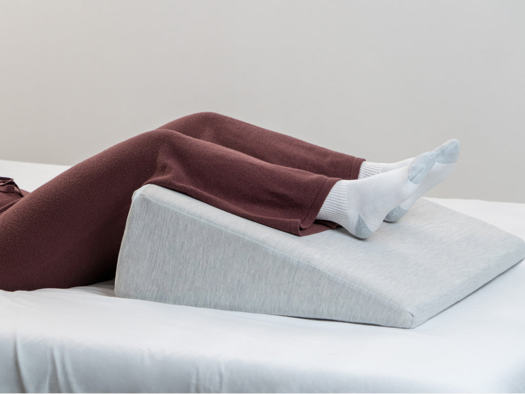 womans legs elevated on Brooklyn Bedding Wedge Pillow in bed
