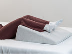 womans legs elevated on Brooklyn Bedding Wedge Pillow in bed