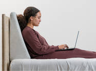 Woman in bed using Brooklyn Bedding Wedge Pillow
