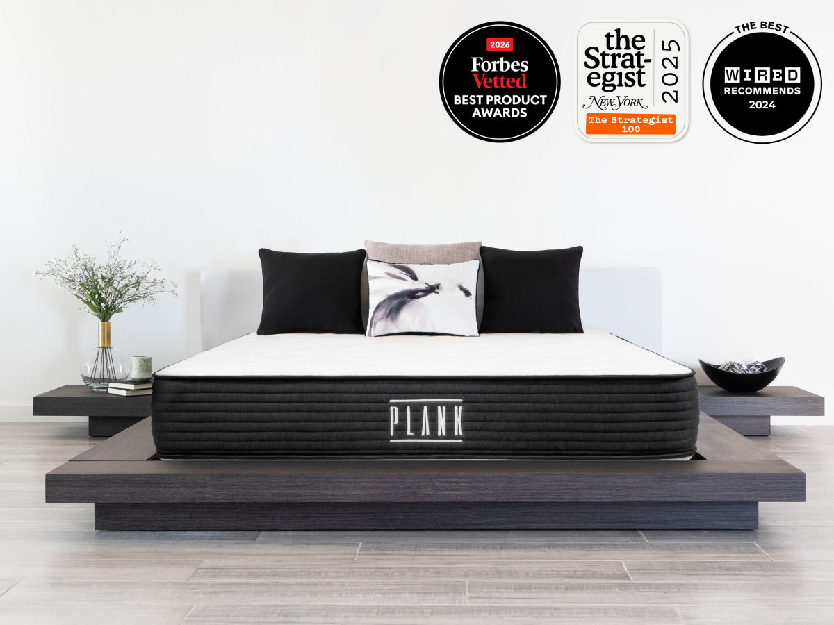 Brooklyn Bedding Plank Firm Mattress on a bed with badges reading “2026 Forbes Vetted Best Product Awards,” “The Strategist 2025,” and “WIRED Recommends 2024.”