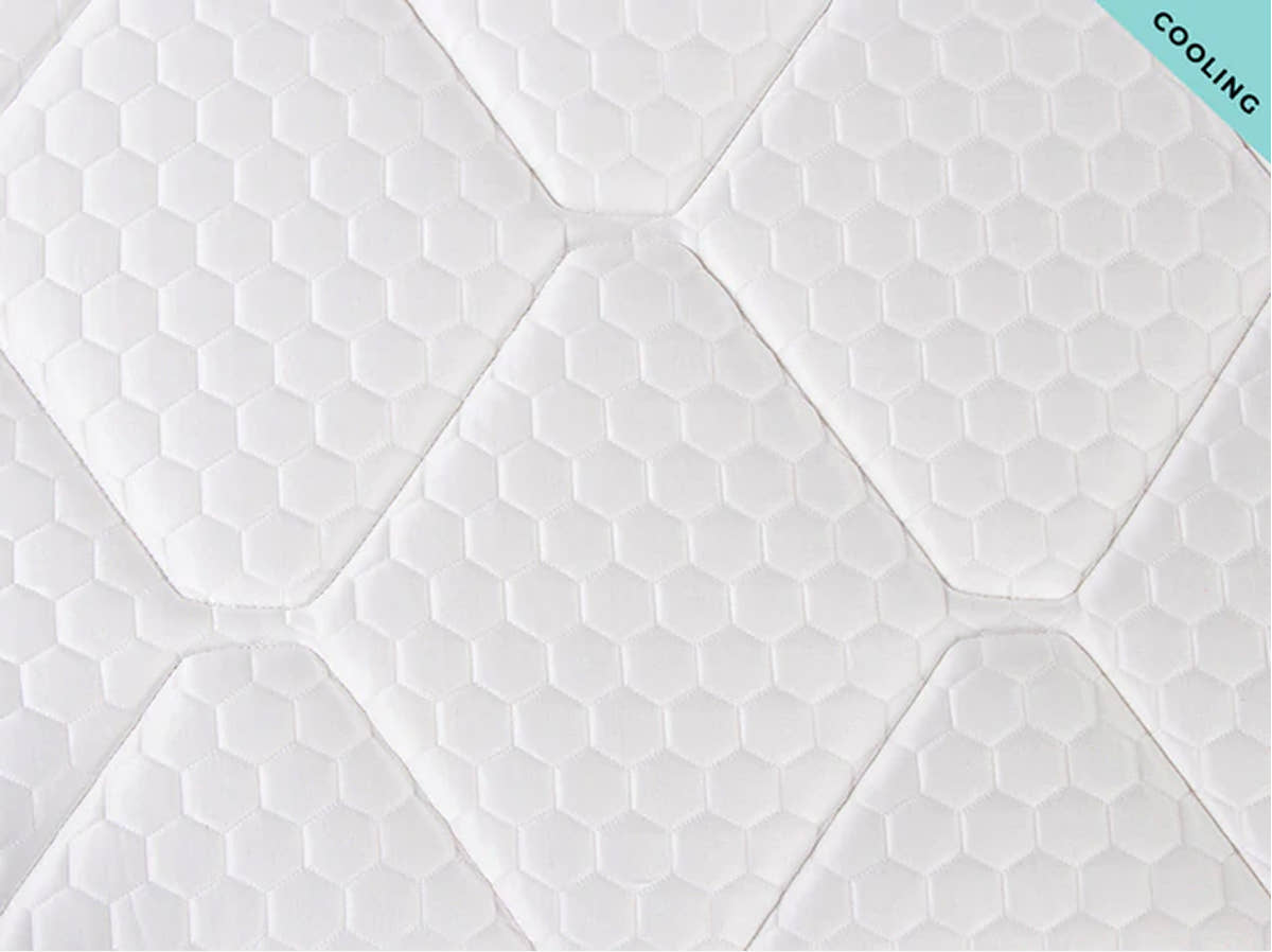 Close-up of the Brooklyn Bedding Plank Firm Luxe cooling surface with white hexagon pattern and tufted stitching, with a “Cooling” corner tag.