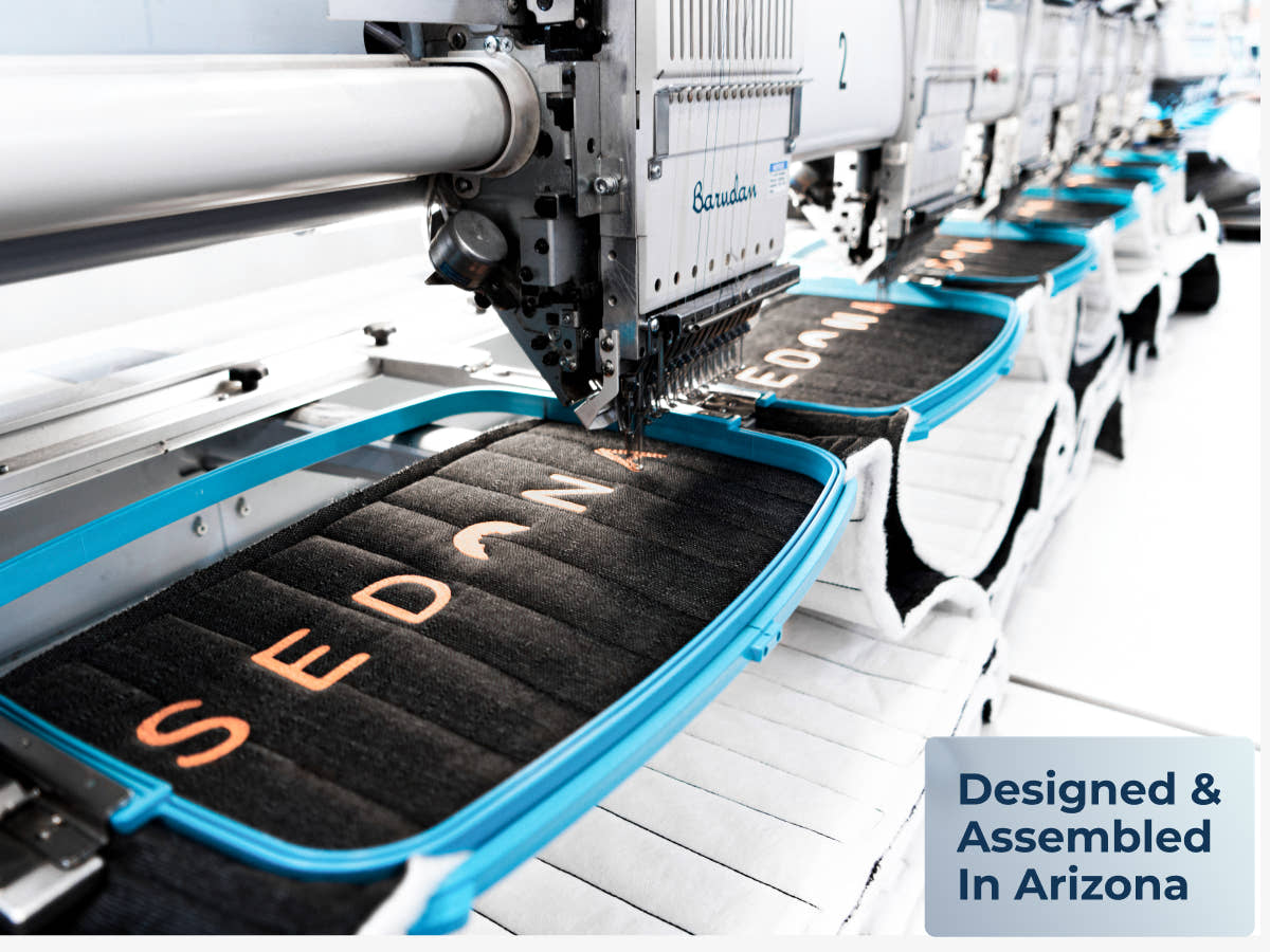 Close-up of Sedona Elite mattress panels being embroidered on a factory machine, with a badge reading “Designed & Assembled In Arizona.”
