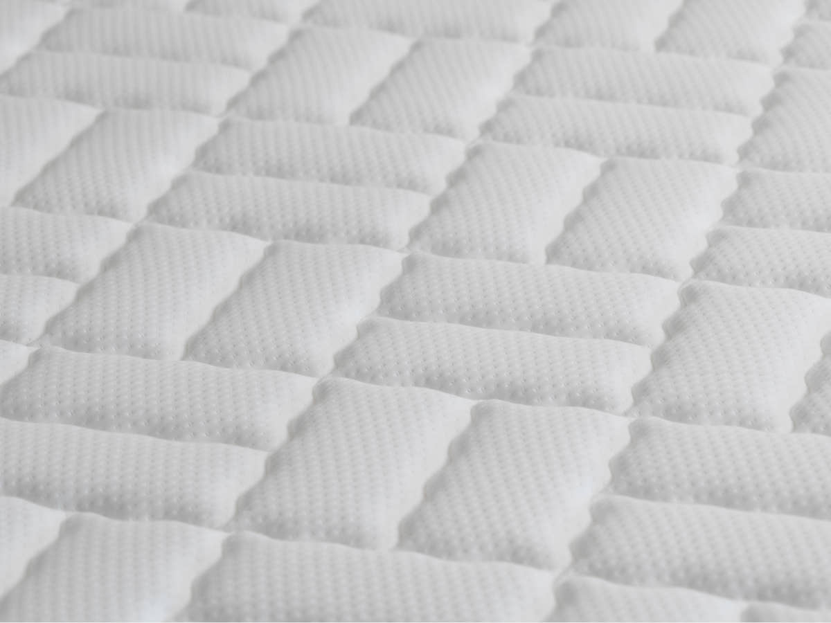 Extreme close-up of the Brooklyn Bedding Titan Plus Core mattress quilted cover fabric, showing a white diamond-pattern stitched surface texture.
