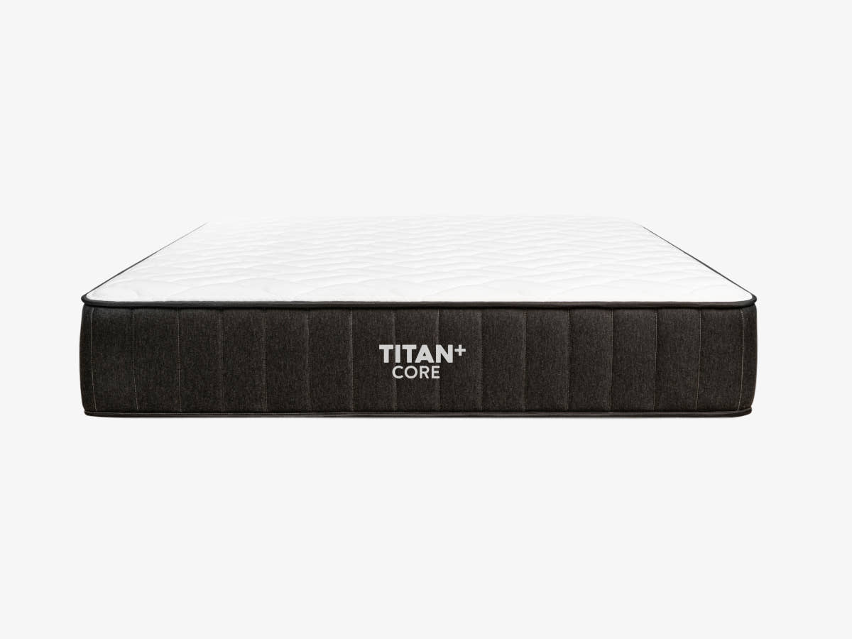 Brooklyn Bedding Titan Plus Core mattress shown in a straight-on front profile view against a light gray background, with a white quilted top and charcoal gray ribbed side panel displaying the Titan+ Core logo.