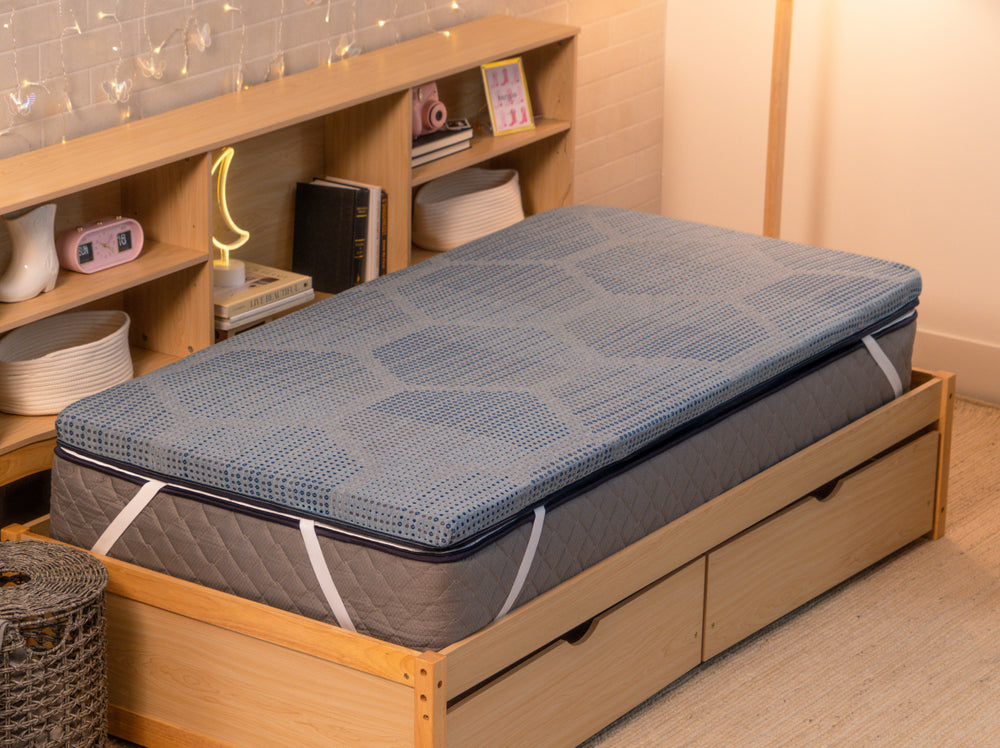 Angled view of the CopperFlex 201 Mattress Topper secured with elastic straps on a wooden bed frame