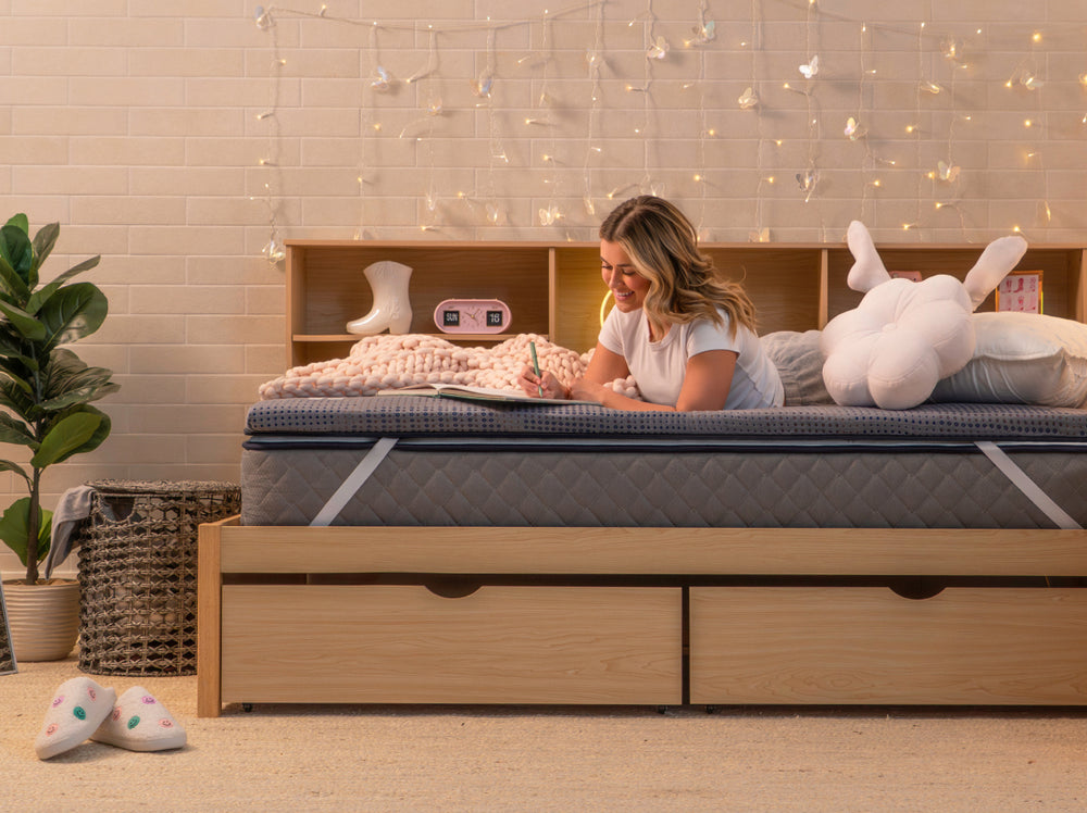 Person lying on their stomach on the CopperFlex 201 Mattress Topper while writing in a notebook.