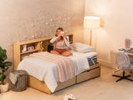 Candid shot of woman sitting on Brooklyn Bedding CopperFlex® 301 Mattress Topper taking photo