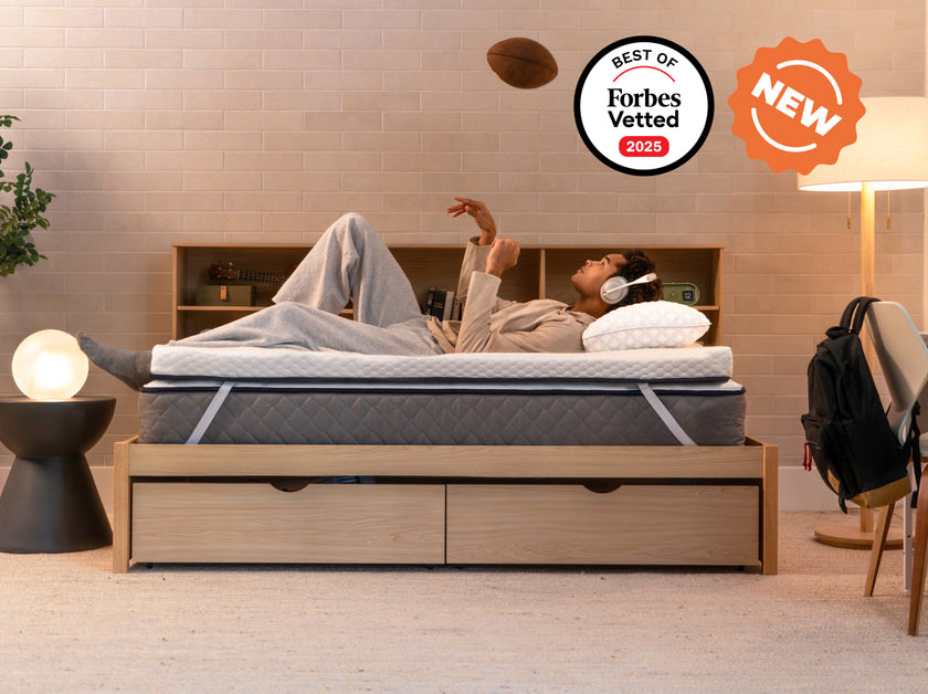 Person lying on the CopperFlex 301 Mattress Topper wearing headphones on a bed with storage frame.
