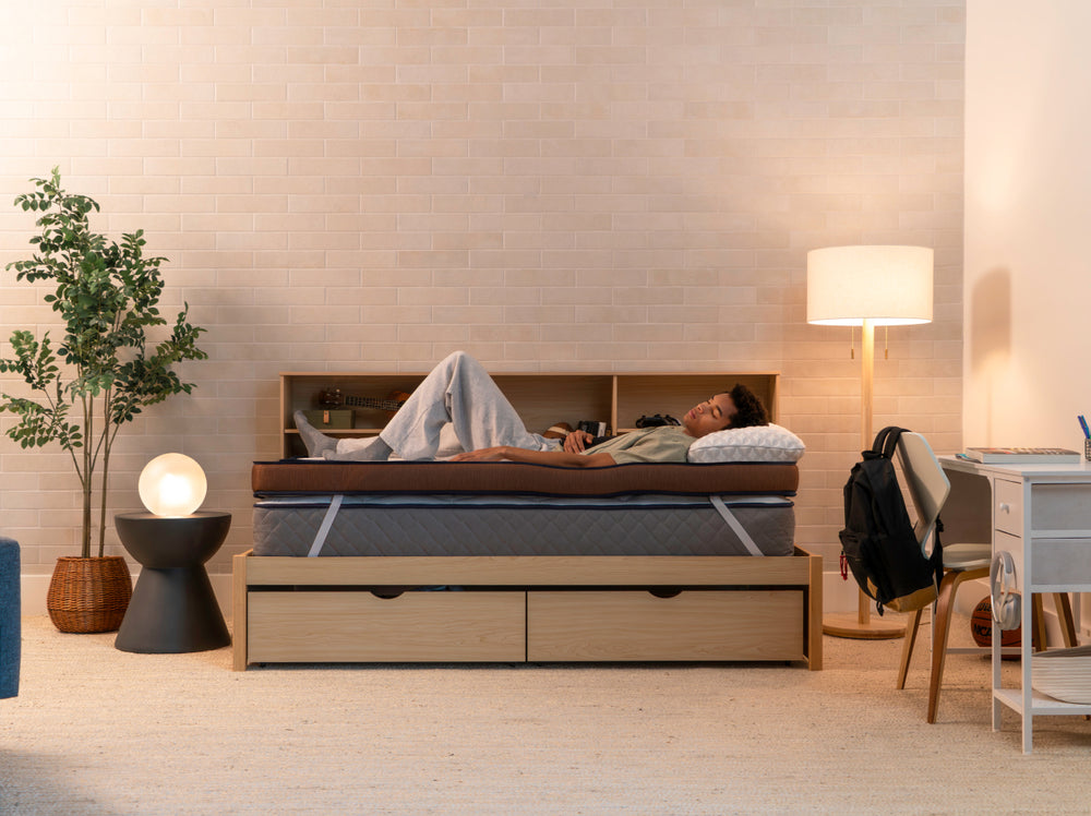 Person resting on the CopperFlex 401 Mattress Topper on a bed in a softly lit bedroom.”