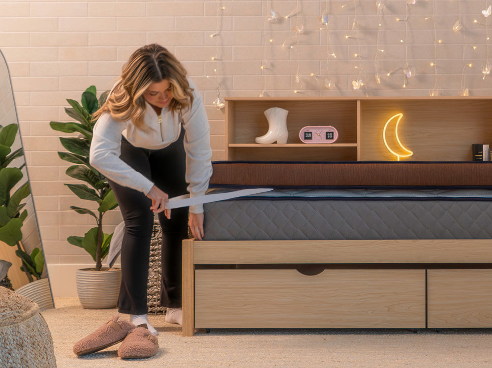 Person attaching the elastic corner strap of the CopperFlex 401 Mattress Topper to a mattress.