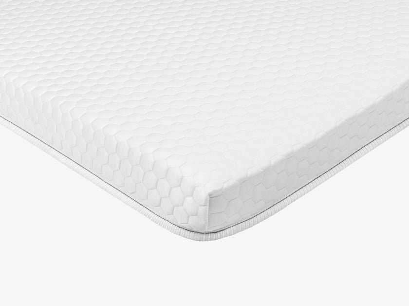Side view of a white quilted mattress topper 