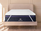 Microcoil Mattress topper placed on a bed with upholstered headboard, showing full fit and elastic corner straps.