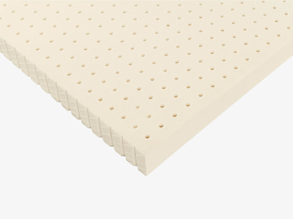 Angled view of a perforated Talalay latex mattress topper with ventilated hole pattern.
