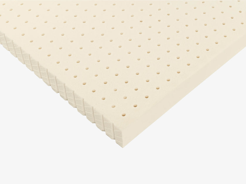 Angled view of a perforated Talalay latex mattress topper with ventilated hole pattern.