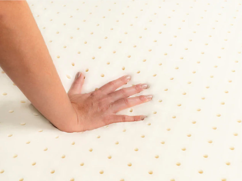 Hand pressing into perforated Talalay latex topper to demonstrate responsive cushioning.