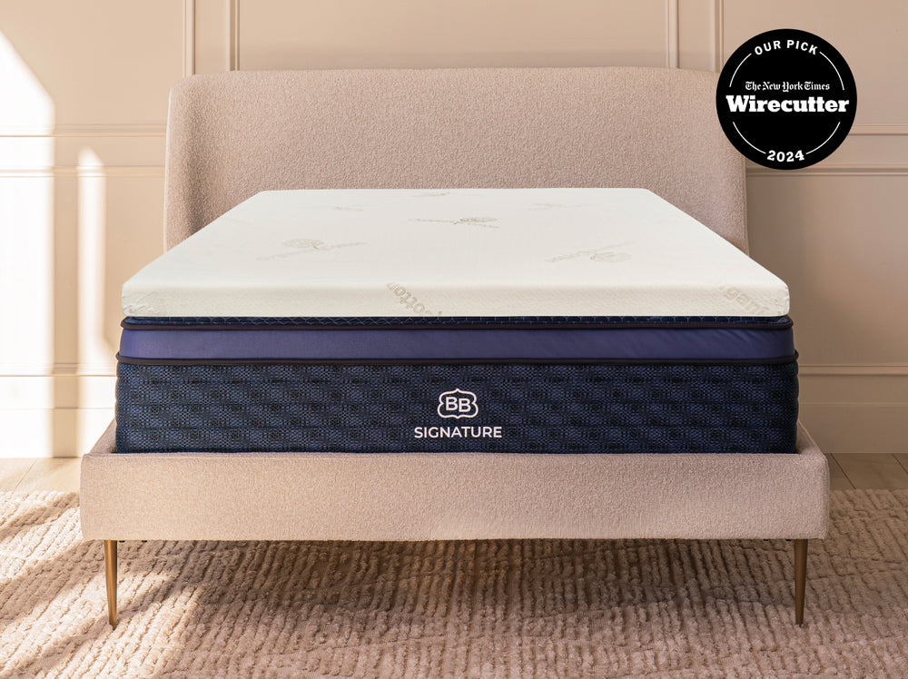 Talalay latex mattress topper placed on a bed with upholstered headboard in a bedroom setting.
