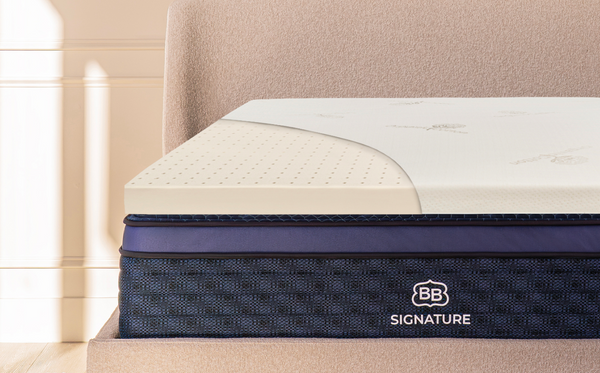 Talalay latex mattress topper placed on a bed with upholstered headboard in a bedroom setting.