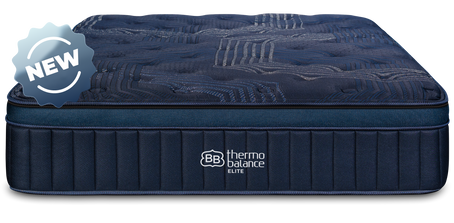 Smiling couple sitting on a navy blue ThermoBalance Elite mattress holding coffee mugs. Text overlay: 