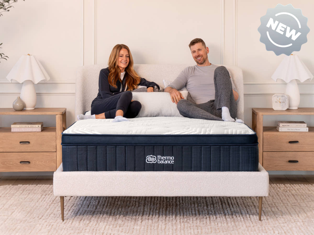 Brooklyn Bedding ThermoBalance LX with two people sitting on the bed, with a badge reading “NEW.”