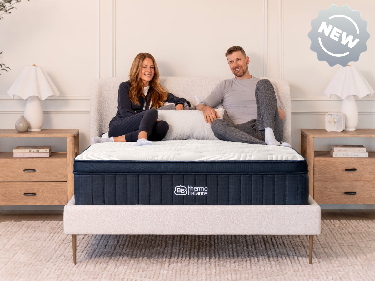 Brooklyn Bedding ThermoBalance LX with two people sitting on the bed, with a badge reading “NEW.”
