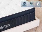 Brooklyn Bedding ThermoBalance LX Elite Mattress corner close-up showing the white quilted top and dark blue side panel on a cream bed frame.
