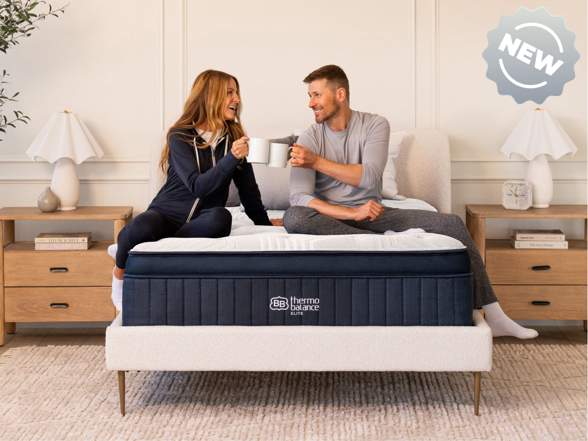 Brooklyn Bedding ThermoBalance LX Elite Mattress with two people sitting on the bed, with a badge reading “NEW.”