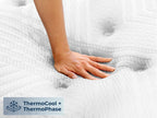 Brooklyn Bedding ThermoBalance LX Elite Mattress close-up with a hand pressing into the white quilted surface, with a badge reading “ThermoCool + ThermoPhase.”
